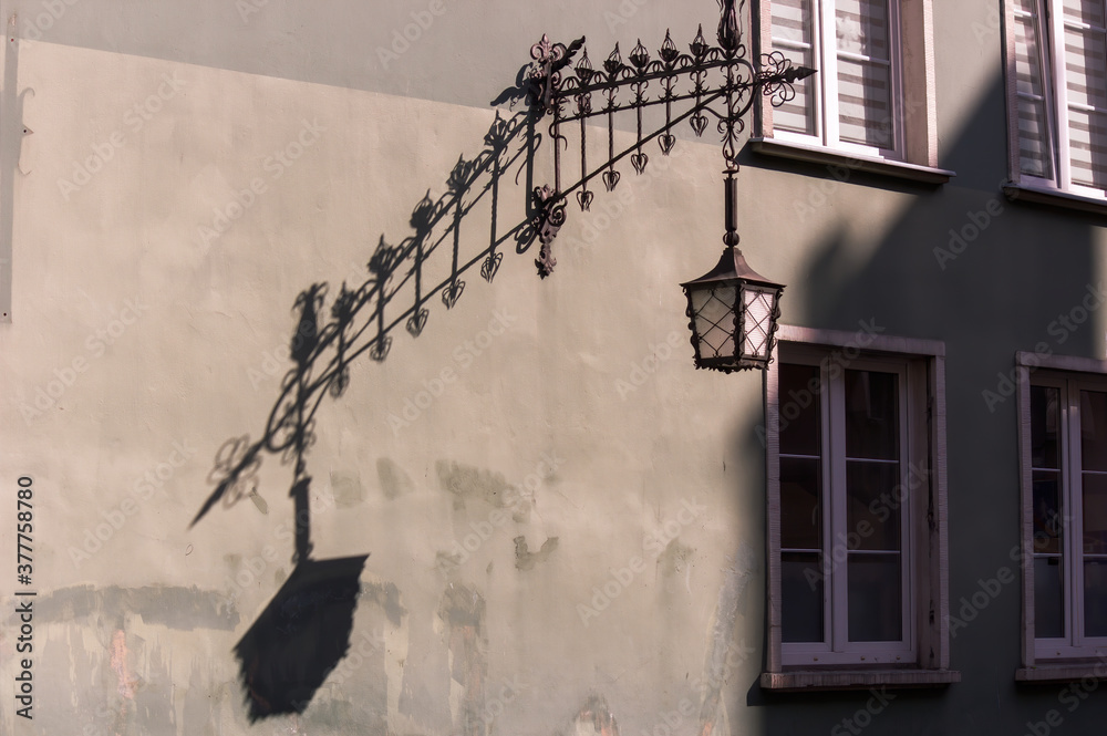 Gdansk, North Poland: An artistic close up shot of lamp with hard shadow reflection against closed windows in the background at the old town Gdansk, North Poland: An artistic close up shot of lamp with hard shadow reflection against closed windows in the background at the old town