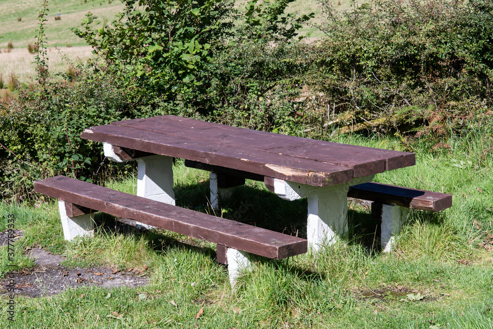 Side on view of wooden picnic table with two benches in nature. Hiking and adventure. Bench outdoors. Side on view of wooden picnic table with two benches in nature. Hiking and adventure. Bench outdoors.