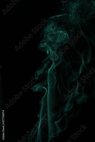 green smoke from incense on a black background