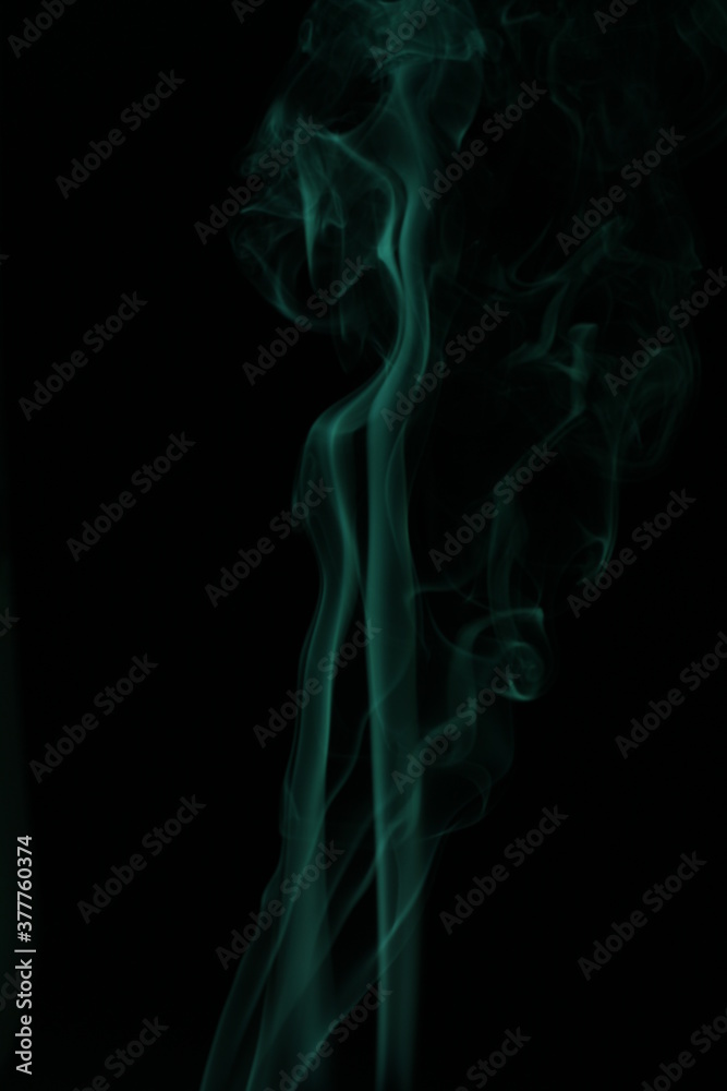 green smoke from incense on a black background
