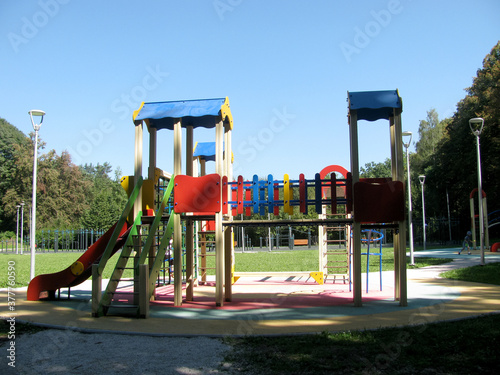 Empty multi-colored Playground in the Park among the grass and trees.