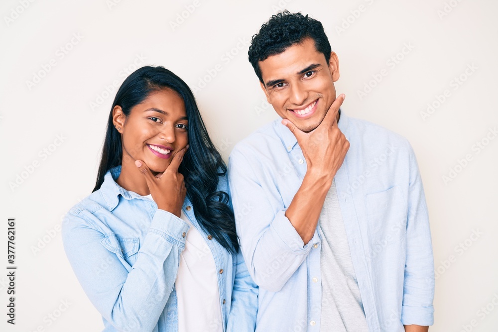 Beautiful latin young couple wearing casual clothes looking confident at the camera smiling with crossed arms and hand raised on chin. thinking positive. Beautiful latin young couple wearing casual clothes looking confident at the camera smiling with crossed arms and hand raised on chin. thinking positive.