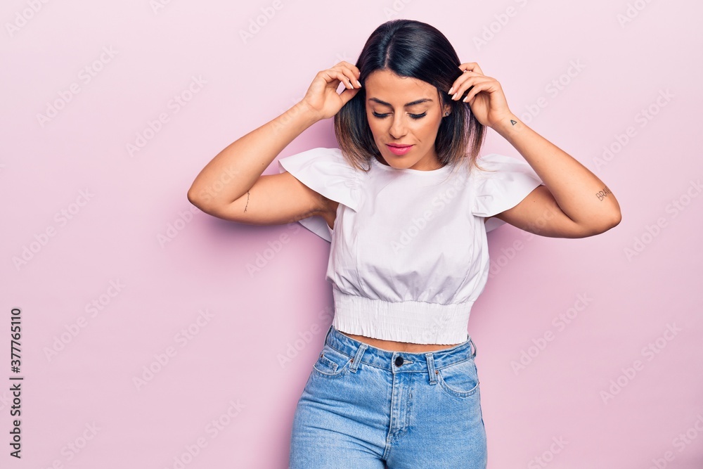 Young beautiful brunette woman wearing casual clothes smiling happy and confident. Standing with smile on face over isolated pink background