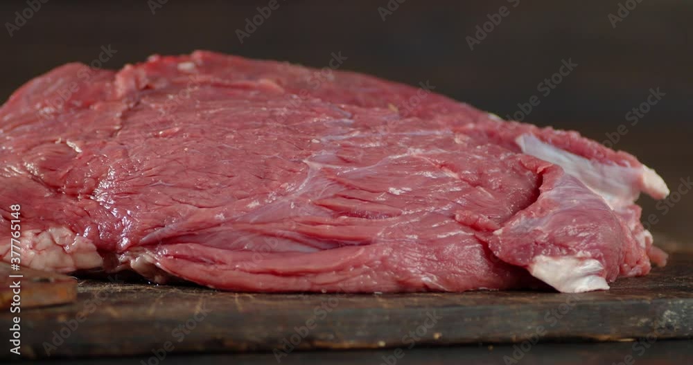 A piece of fresh raw beef slowly rotates on the table. A piece of fresh raw beef slowly rotates on the table.