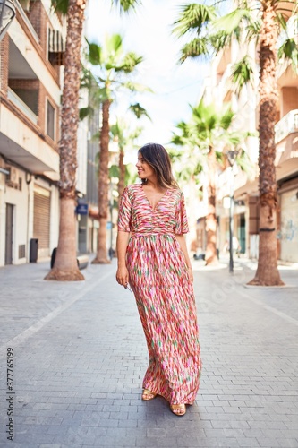 Beautiful young woman wearing fashionable clothes walking down the street