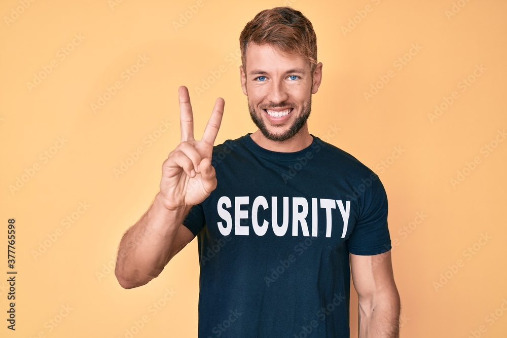 Young caucasian man wearing security t shirt showing and pointing up with fingers number two while smiling confident and happy. Young caucasian man wearing security t shirt showing and pointing up with fingers number two while smiling confident and happy.