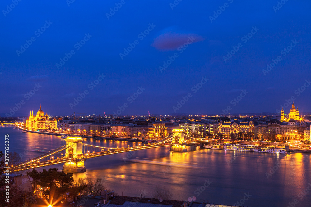 Twilight over the city of Budapest.  Seen is the Danube River and the illuminated Hungarian Parliament building and the Chain Bridge