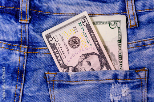 American five dollar banknotes in a pocket of blue jeans