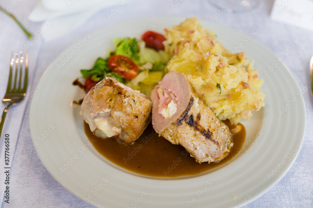 Stuffed meat with side dish and mashed potatoes.