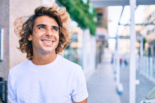 Young handsome hispanic man smiling happy walking at street of city