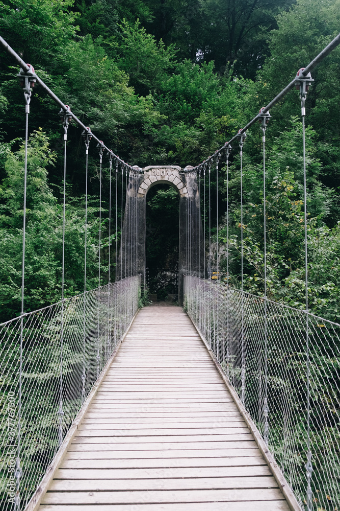 Inside view of the Holtzarte suspension bridge with wooden floor and lush forest in the background Inside view of the Holtzarte suspension bridge with wooden floor and lush forest in the background