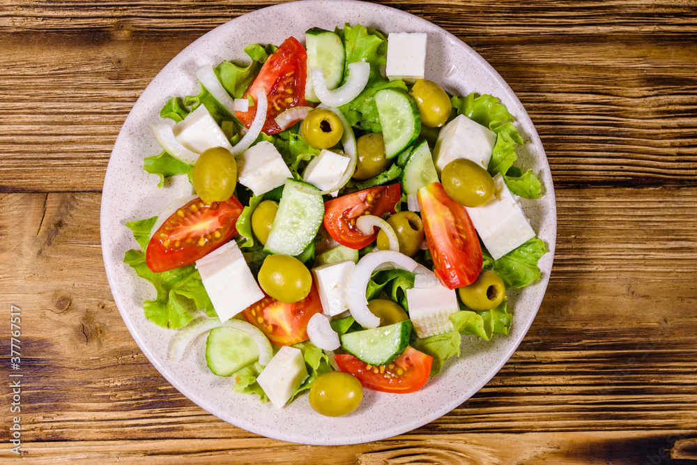 Ceramic plate with greek salad on wooden table. Top view Ceramic plate with greek salad on wooden table. Top view