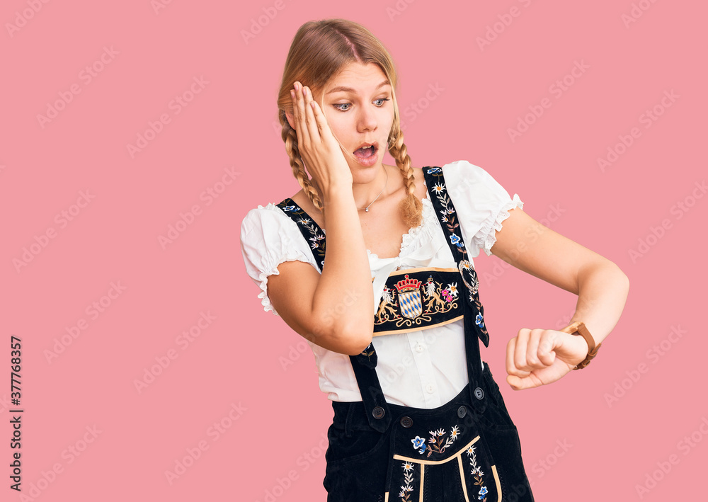 Young beautiful blonde woman wearing oktoberfest dress looking at the watch time worried, afraid of getting late