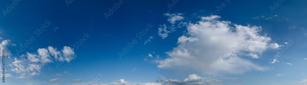 White cumulus and rainbow clouds in blue sky panoramic high resolution background