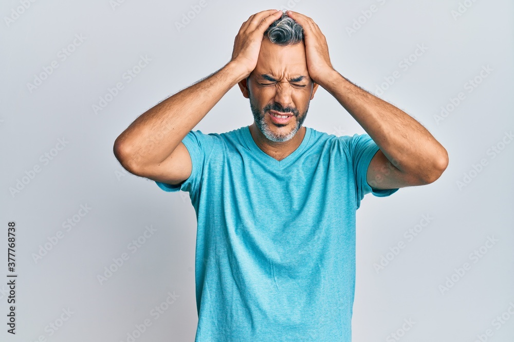 Middle age grey-haired man wearing casual clothes suffering from headache desperate and stressed because pain and migraine. hands on head. Middle age grey-haired man wearing casual clothes suffering from headache desperate and stressed because pain and migraine. hands on head.