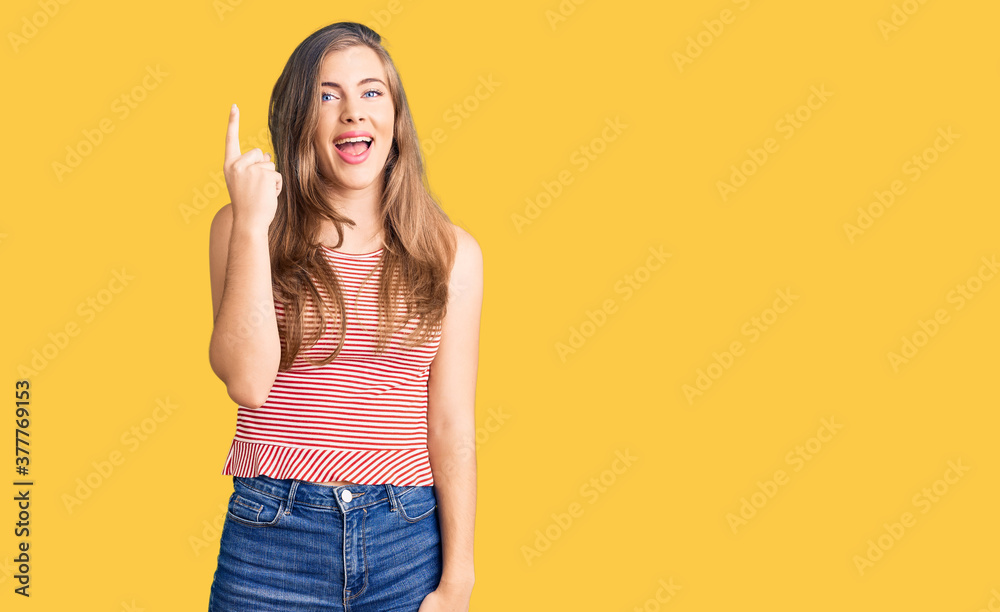 Beautiful caucasian young woman wearing casual clothes pointing finger up with successful idea. exited and happy. number one. Beautiful caucasian young woman wearing casual clothes pointing finger up with successful idea. exited and happy. number one.