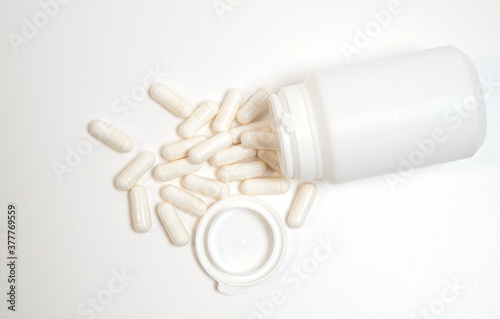 white plastic tube without inscriptions from pills on a white background and white pills near
