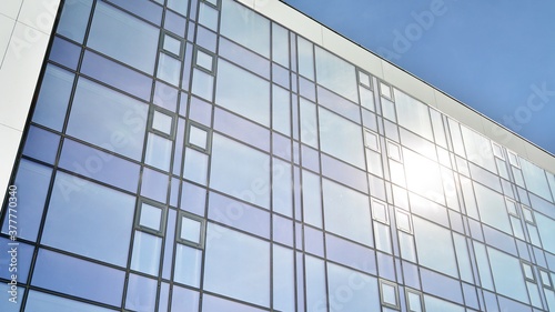 Blue curtain wall made of toned glass and steel constructions under blue sky. A fragment of a building.