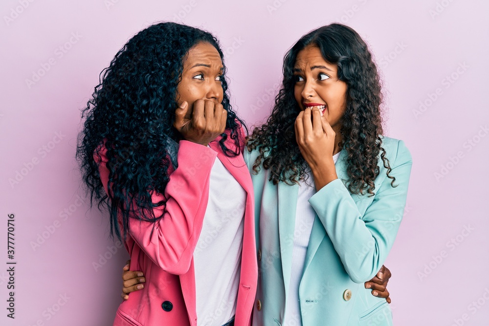 African american mother and daughter wearing business style looking stressed and nervous with hands on mouth biting nails. anxiety problem. African american mother and daughter wearing business style looking stressed and nervous with hands on mouth biting nails. anxiety problem.