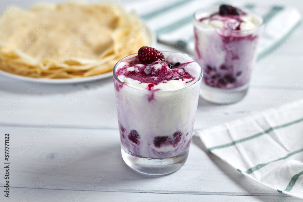 Delicious vanilla ice cream dessert with berry sauce next to delicious pancakes. Selective focus. Delicious vanilla ice cream dessert with berry sauce next to delicious pancakes. Selective focus.