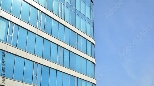 Blue curtain wall made of toned glass and steel constructions under blue sky. A fragment of a building.