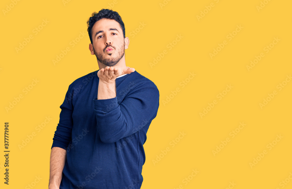 Young hispanic man wearing casual clothes looking at the camera blowing a kiss with hand on air being lovely and sexy. love expression.