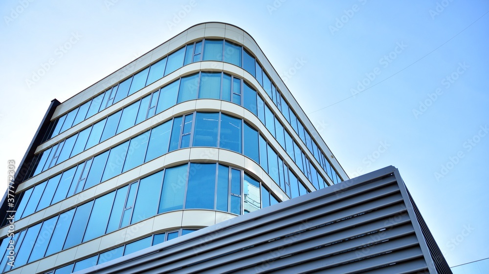 Blue curtain wall made of toned glass and steel constructions under blue sky. A fragment of a building. Blue curtain wall made of toned glass and steel constructions under blue sky. A fragment of a building.
