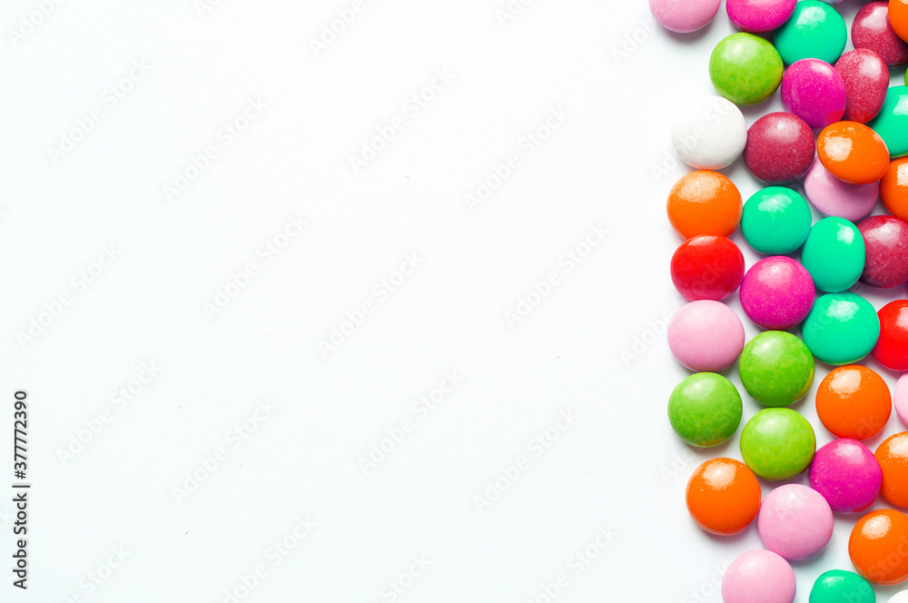 Colored balls of sugar on a white background. Chocolate candies covered with multicolored sugar glaze. Place for text