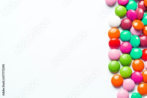 Colored balls of sugar on a white background. Chocolate candies covered with multicolored sugar glaze. Place for text