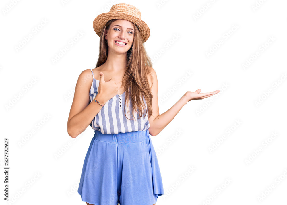 Young beautiful blonde woman wearing summer hat showing palm hand and doing ok gesture with thumbs up, smiling happy and cheerful Young beautiful blonde woman wearing summer hat showing palm hand and doing ok gesture with thumbs up, smiling happy and cheerful