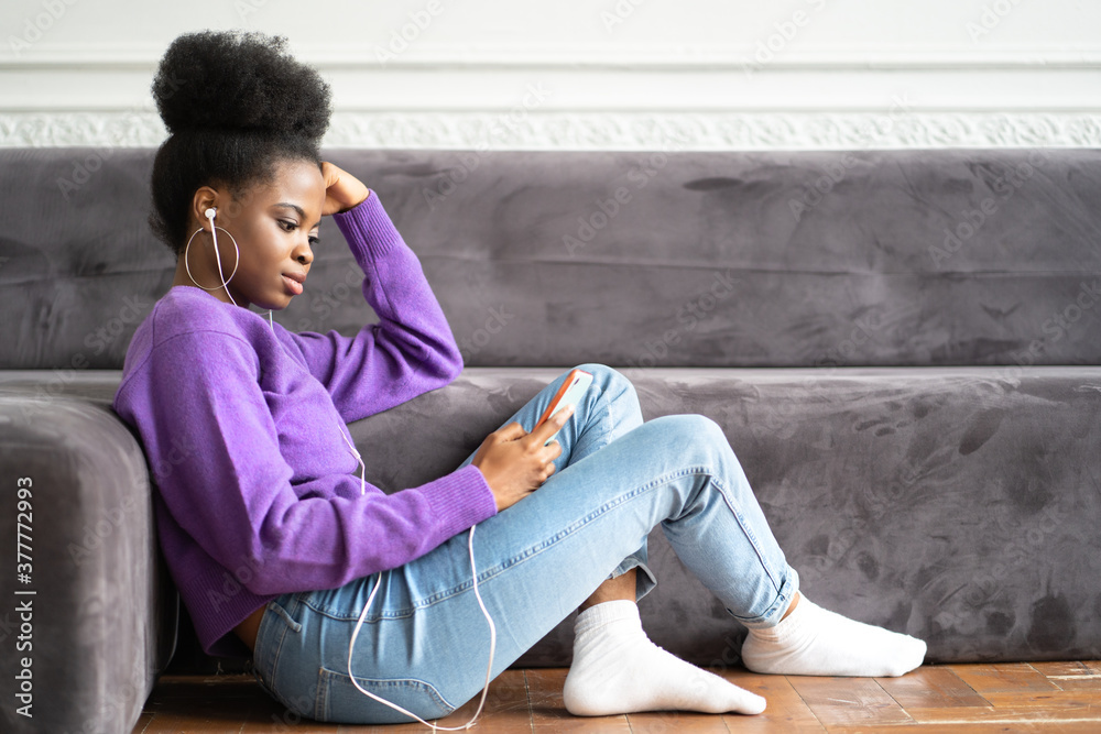 Φωτογραφία African American millennial young woman in purple sweater sitting on the floor,