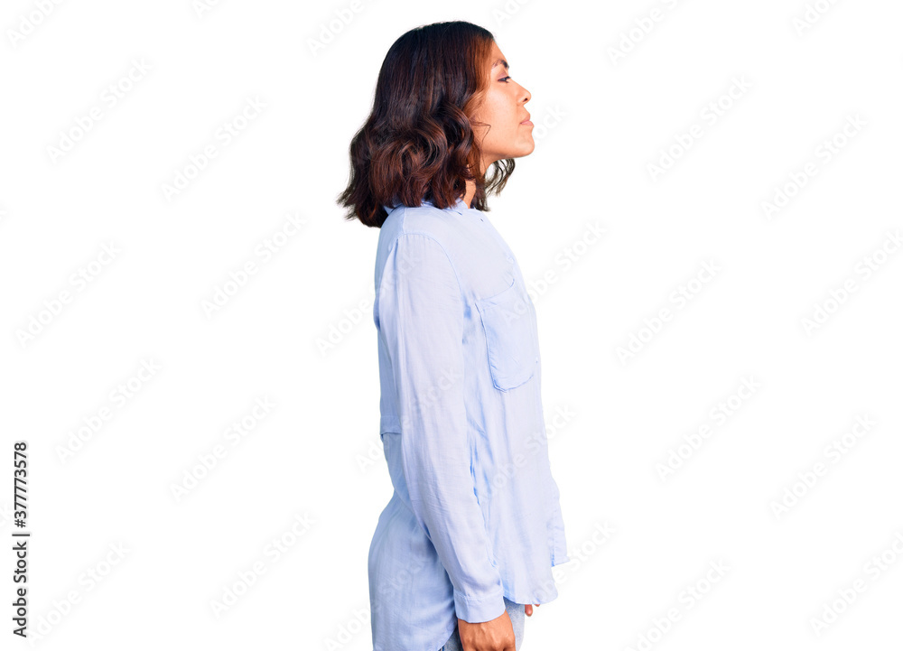 Young beautiful mixed race woman wearing casual business shirt looking to side, relax profile pose with natural face with confident smile. Young beautiful mixed race woman wearing casual business shirt looking to side, relax profile pose with natural face with confident smile.