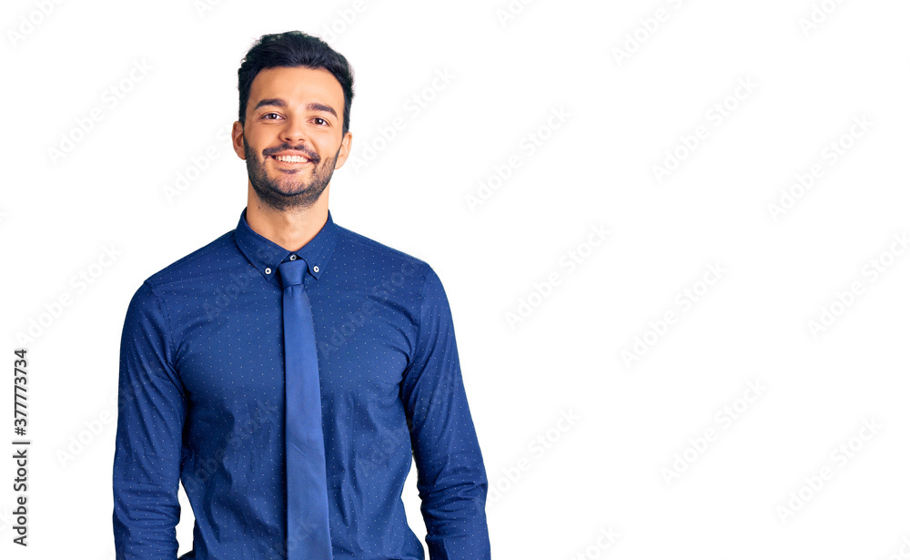 Young handsome hispanic man wearing business clothes looking positive and happy standing and smiling with a confident smile showing teeth Young handsome hispanic man wearing business clothes looking positive and happy standing and smiling with a confident smile showing teeth