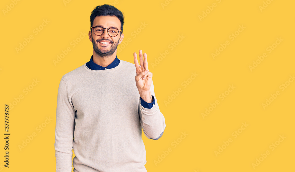 Young handsome hispanic man wearing elegant clothes and glasses showing and pointing up with fingers number three while smiling confident and happy. Young handsome hispanic man wearing elegant clothes and glasses showing and pointing up with fingers number three while smiling confident and happy.