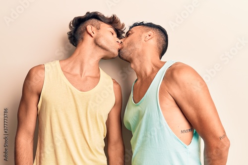 Young couple of men wearing summer clothes. Standing with smile on face kissing over isolated white background