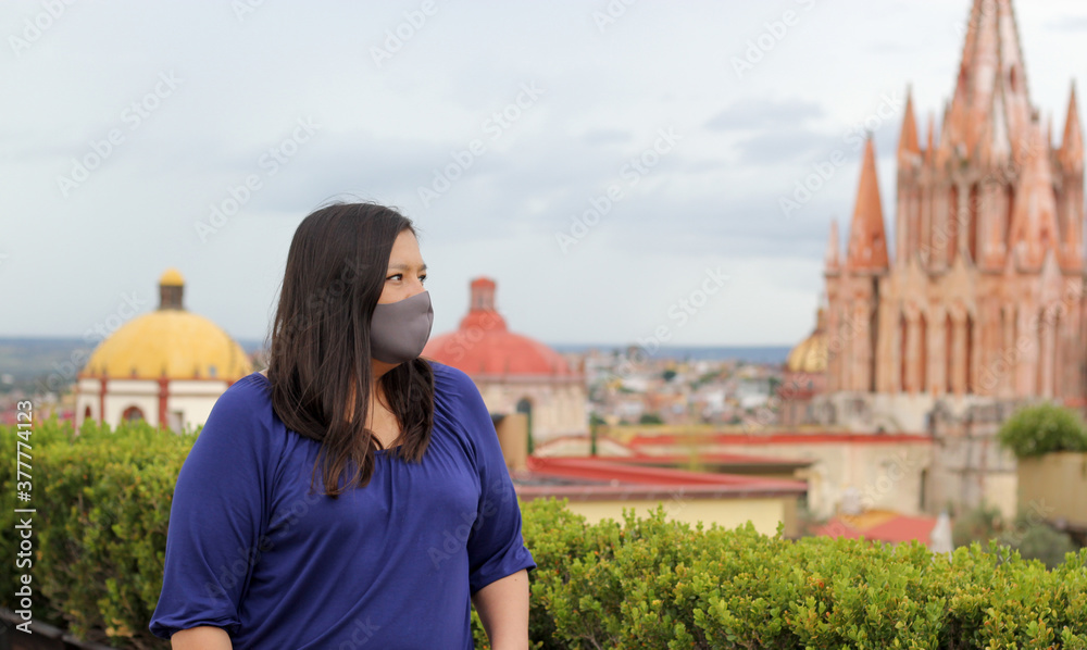 
Selfie with mobile phone of Latina tourist woman with protection mask on terrace with cathedral view in San Miguel de Allende, Guanajuato Mexico
