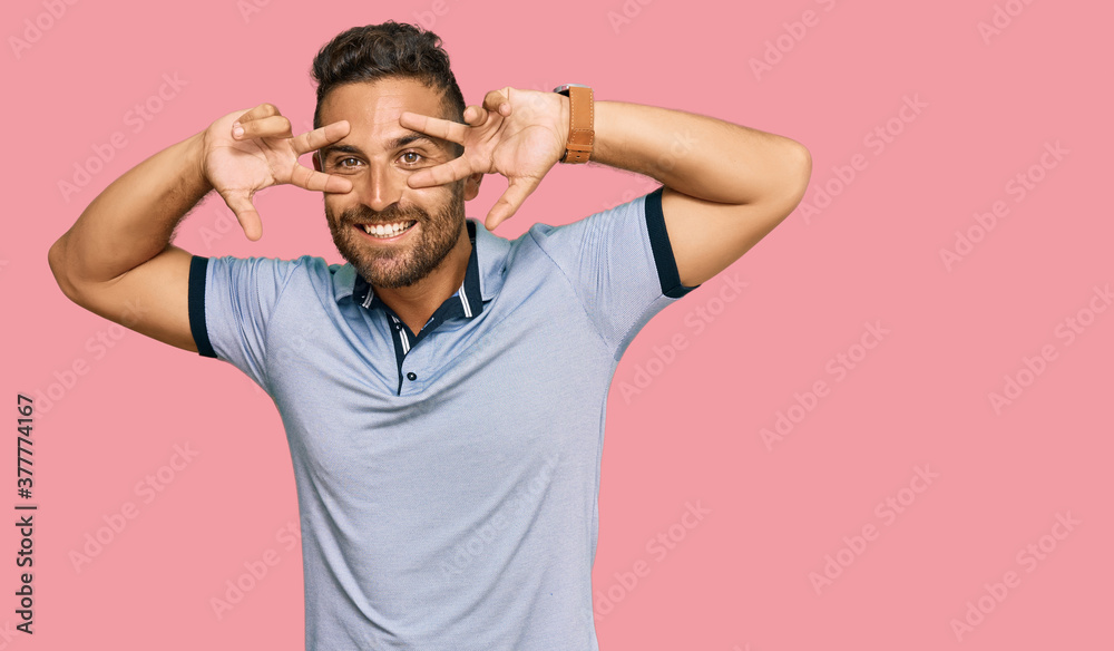 Handsome man with beard wearing casual clothes doing peace symbol with fingers over face, smiling cheerful showing victory Handsome man with beard wearing casual clothes doing peace symbol with fingers over face, smiling cheerful showing victory