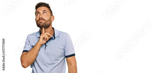 Handsome man with beard wearing casual clothes thinking concentrated about doubt with finger on chin and looking up wondering