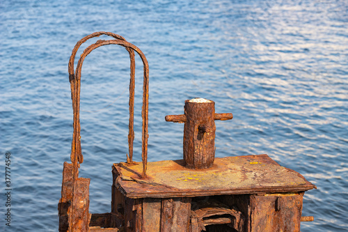 Old rusty bollard in the seaport. Port facilities for mooring vessels. Summer season. photo