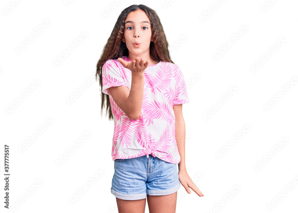 Cute hispanic child girl wearing casual clothes looking at the camera blowing a kiss with hand on air being lovely and sexy. love expression. Cute hispanic child girl wearing casual clothes looking at the camera blowing a kiss with hand on air being lovely and sexy. love expression.
