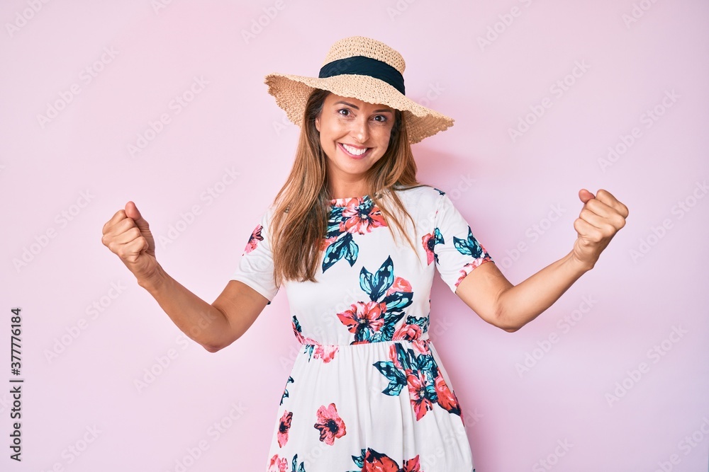 Middle age hispanic woman wearing summer hat screaming proud, celebrating victory and success very excited with raised arms Middle age hispanic woman wearing summer hat screaming proud, celebrating victory and success very excited with raised arms