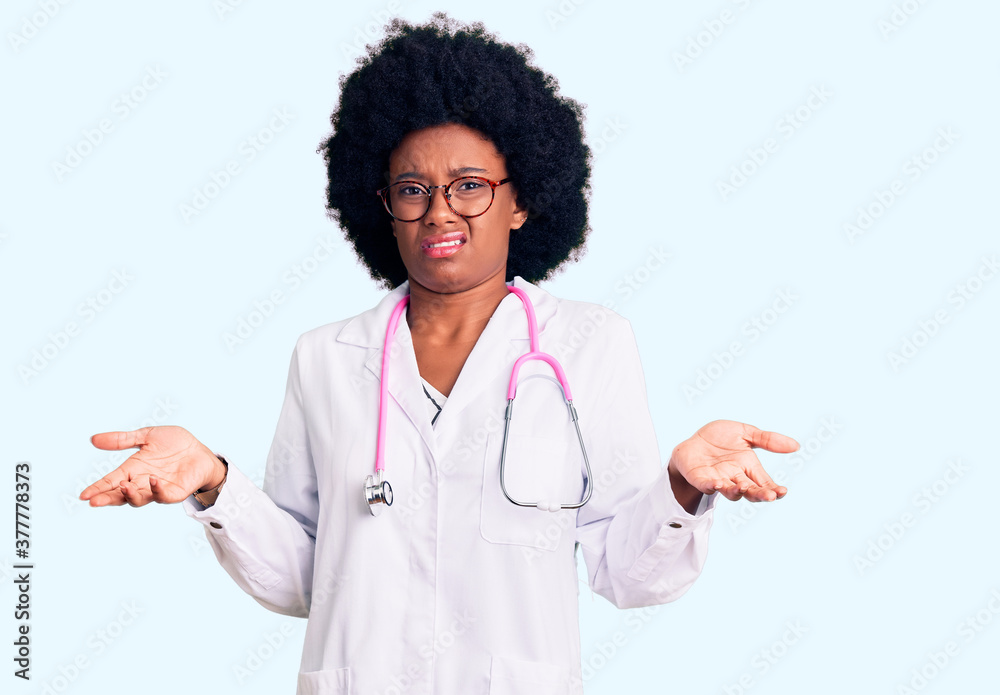 Young african american woman wearing doctor coat and stethoscope clueless and confused with open arms, no idea concept. Young african american woman wearing doctor coat and stethoscope clueless and confused with open arms, no idea concept.