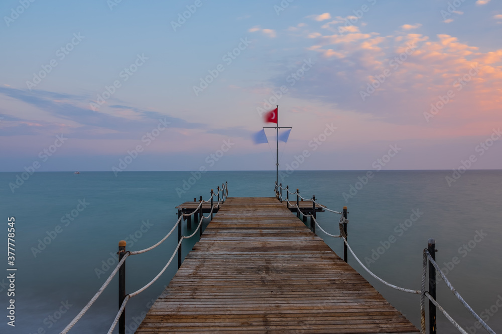 spectacular sunset on a peer in Mediterranean Sea with long exposure and a blurred background. Turkey, Belek, august 2020