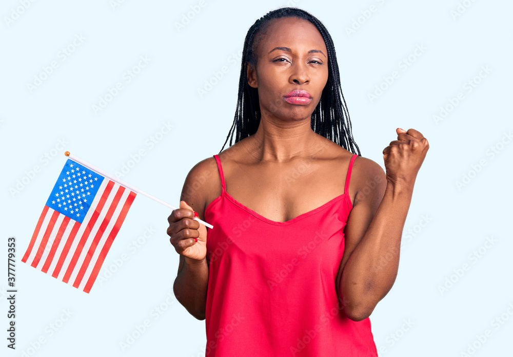 Young african american woman holding united states flag annoyed and frustrated shouting with anger, yelling crazy with anger and hand raised Young african american woman holding united states flag annoyed and frustrated shouting with anger, yelling crazy with anger and hand raised