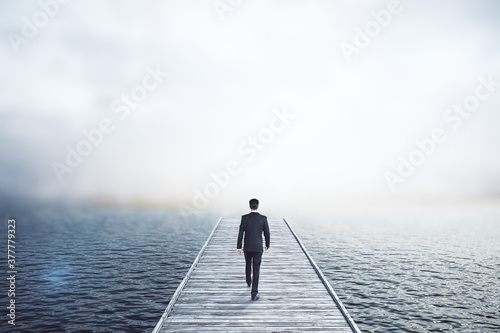 Businessman walking on wooden pier.