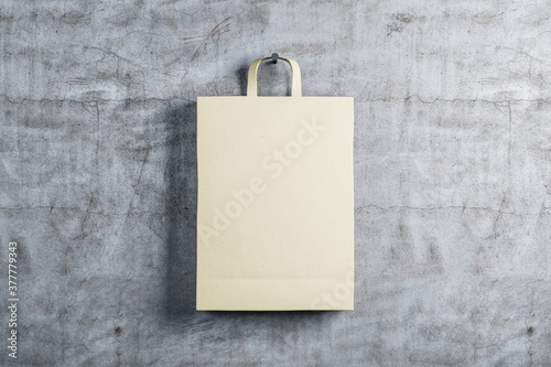 One paper shopping bag on concrete wall background.