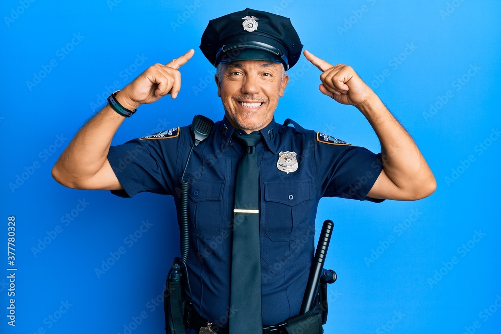 Handsome middle age mature man wearing police uniform smiling pointing to head with both hands finger, great idea or thought, good memory