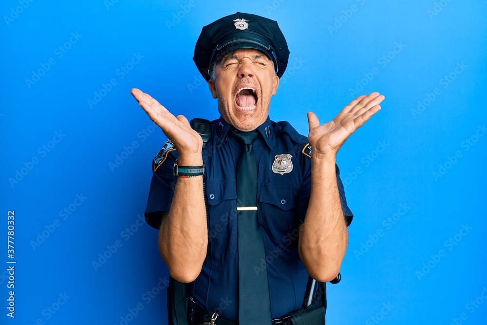 Handsome middle age mature man wearing police uniform celebrating mad and crazy for success with arms raised and closed eyes screaming excited. winner concept Handsome middle age mature man wearing police uniform celebrating mad and crazy for success with arms raised and closed eyes screaming excited. winner concept