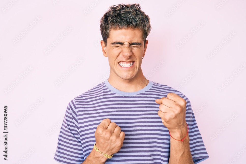 Young handsome man wearing casual clothes celebrating surprised and amazed for success with arms raised and eyes closed