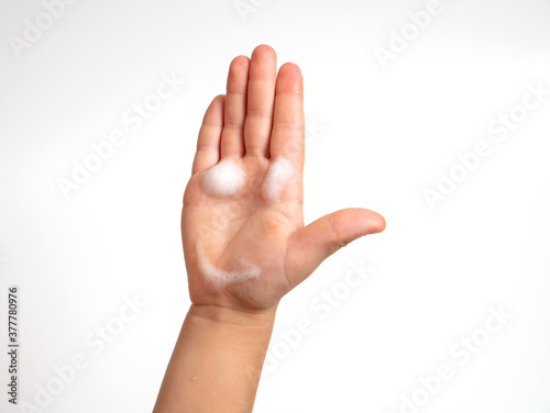children's hand with foam for washing hands in the form of a smiley isolated on white
